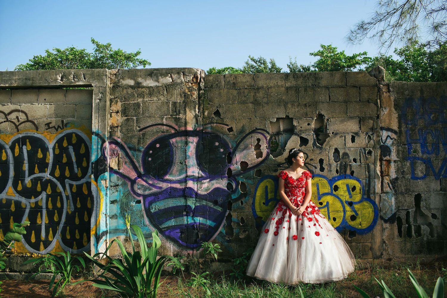 Quinceañera portrait in Playa del Carmen featuring a red floral gown and colorful urban graffiti wall backdrop.