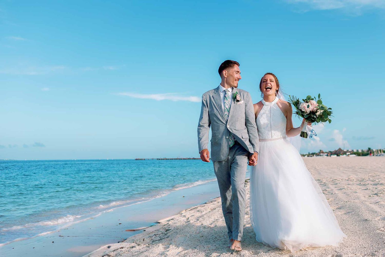 Bride and groom walking along the beach at Majestic Elegance Costa Mujeres after their destination wedding ceremony in Cancun.