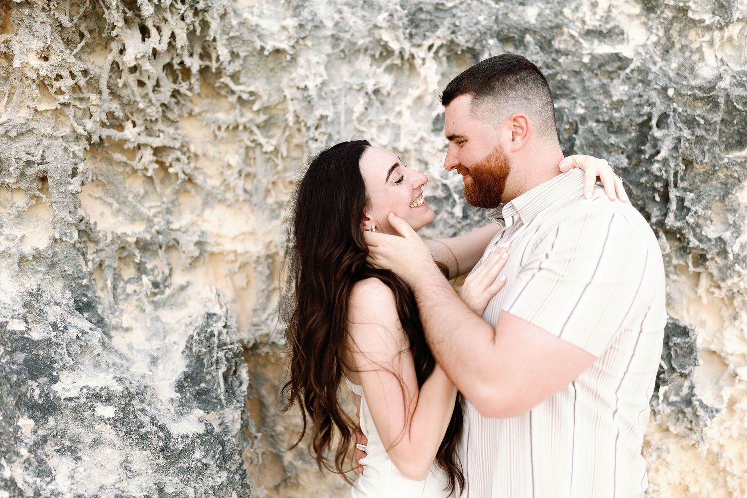 Alexia and Sam smile at each other during their couple’s portrait session among Punta Sur’s limestone rocks.