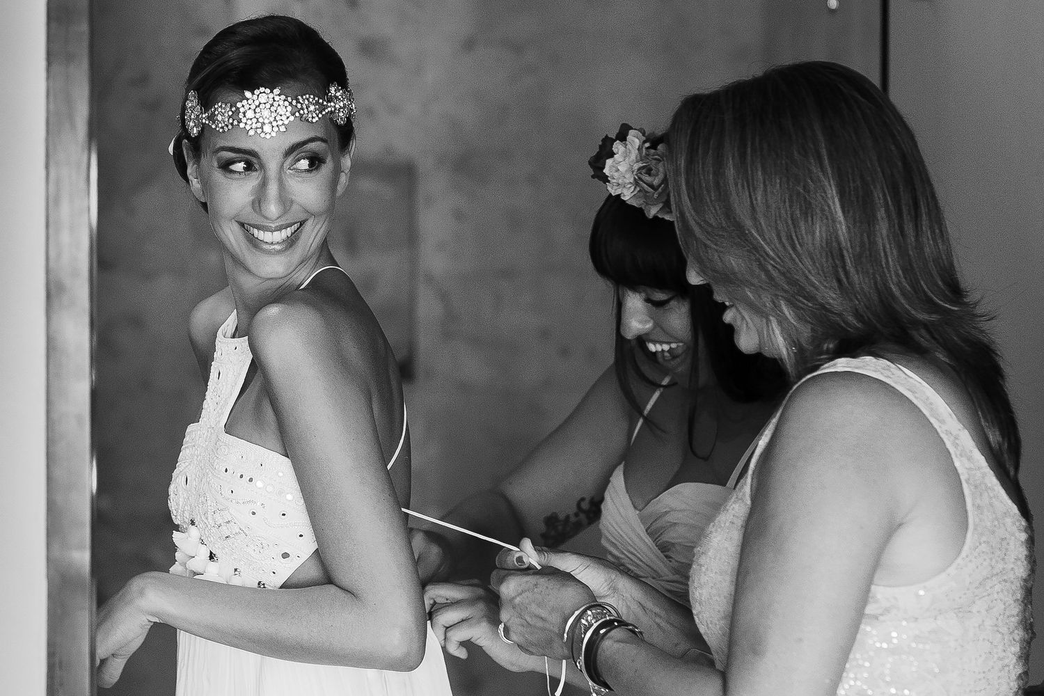 Juliana smiles as her bridesmaids help fasten her wedding dress.