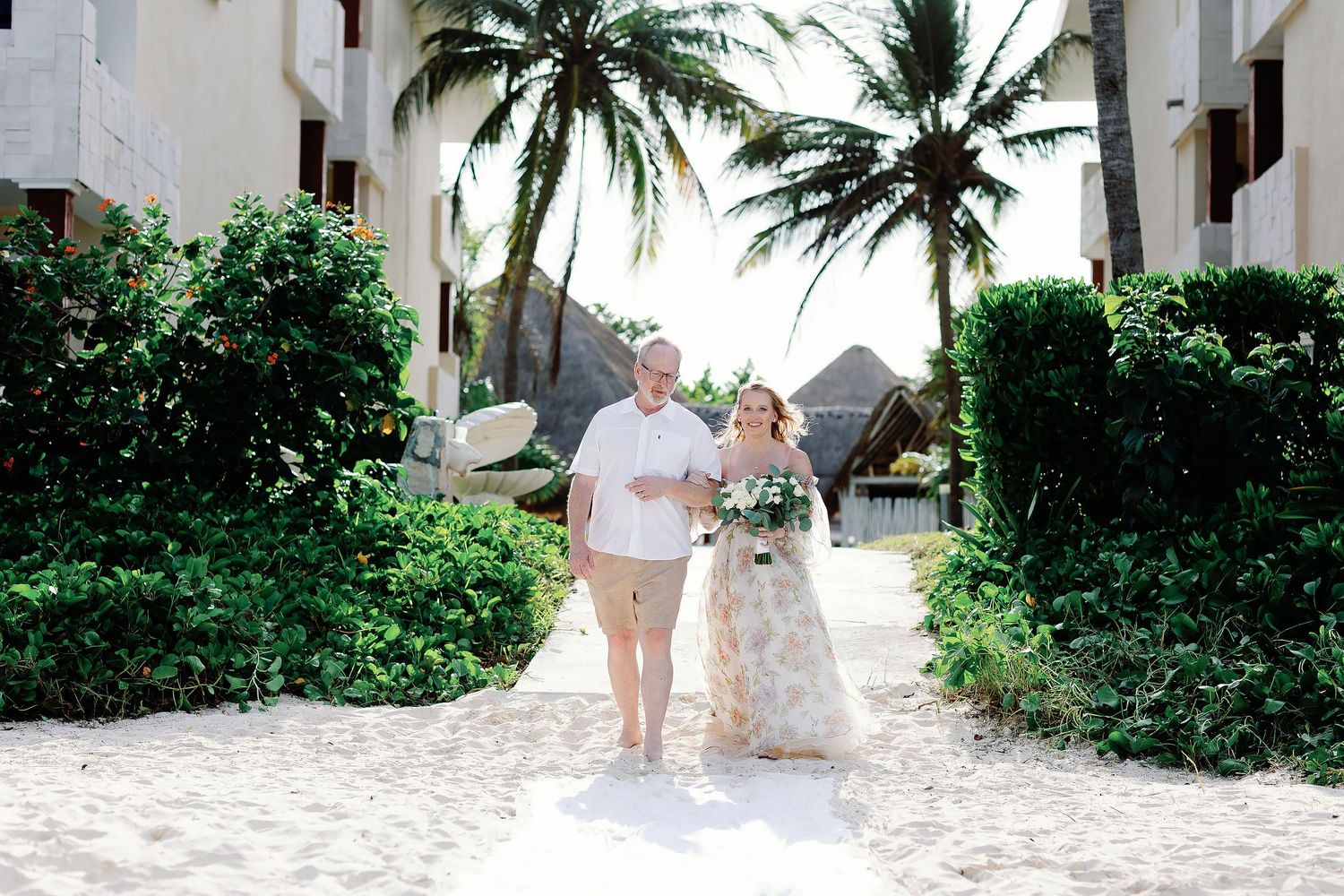 Autumn walking with her father toward her beachfront wedding ceremony at Dreams Sapphire in Puerto Morelos.