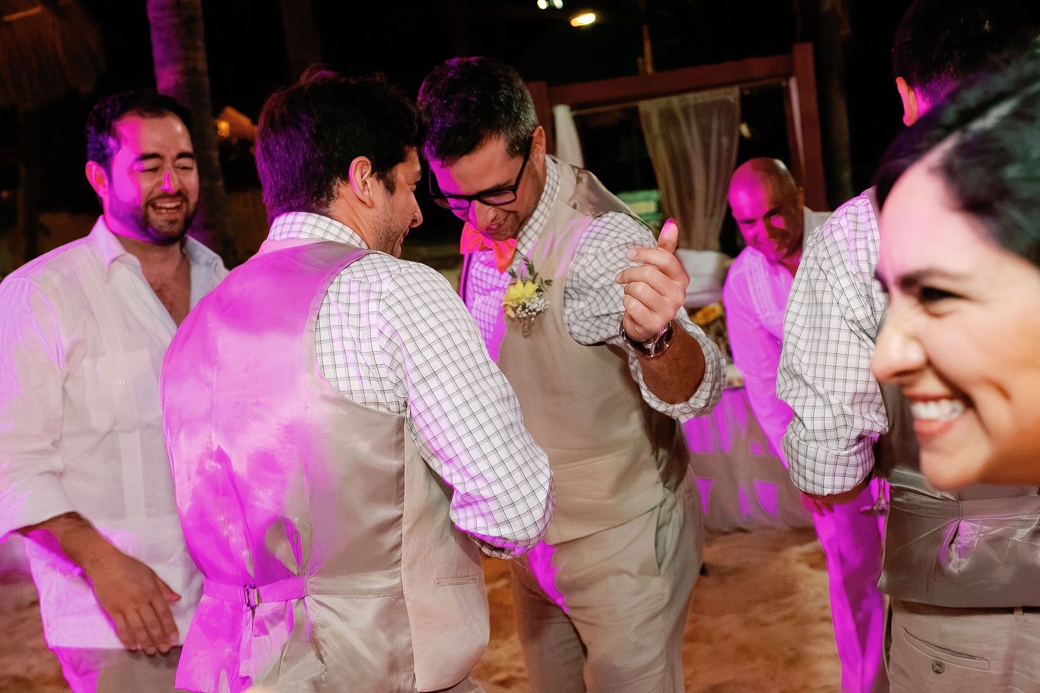 Wedding guests dance together beneath purple party lights at the Isla Mujeres beach reception.
