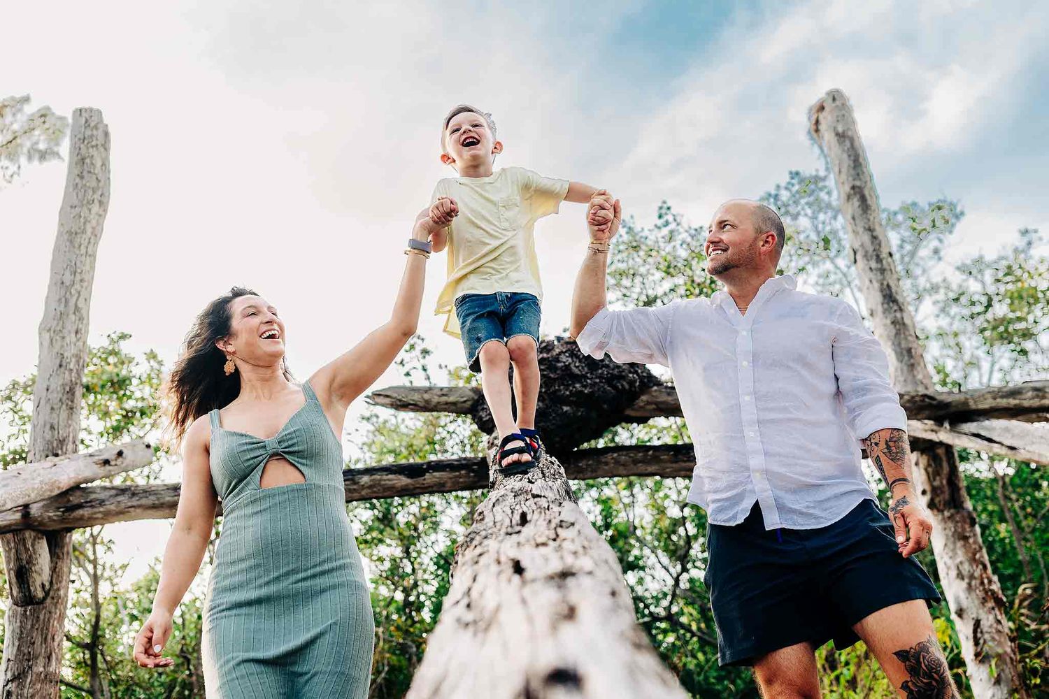 Parents holding hands with their child during a natural family beach session