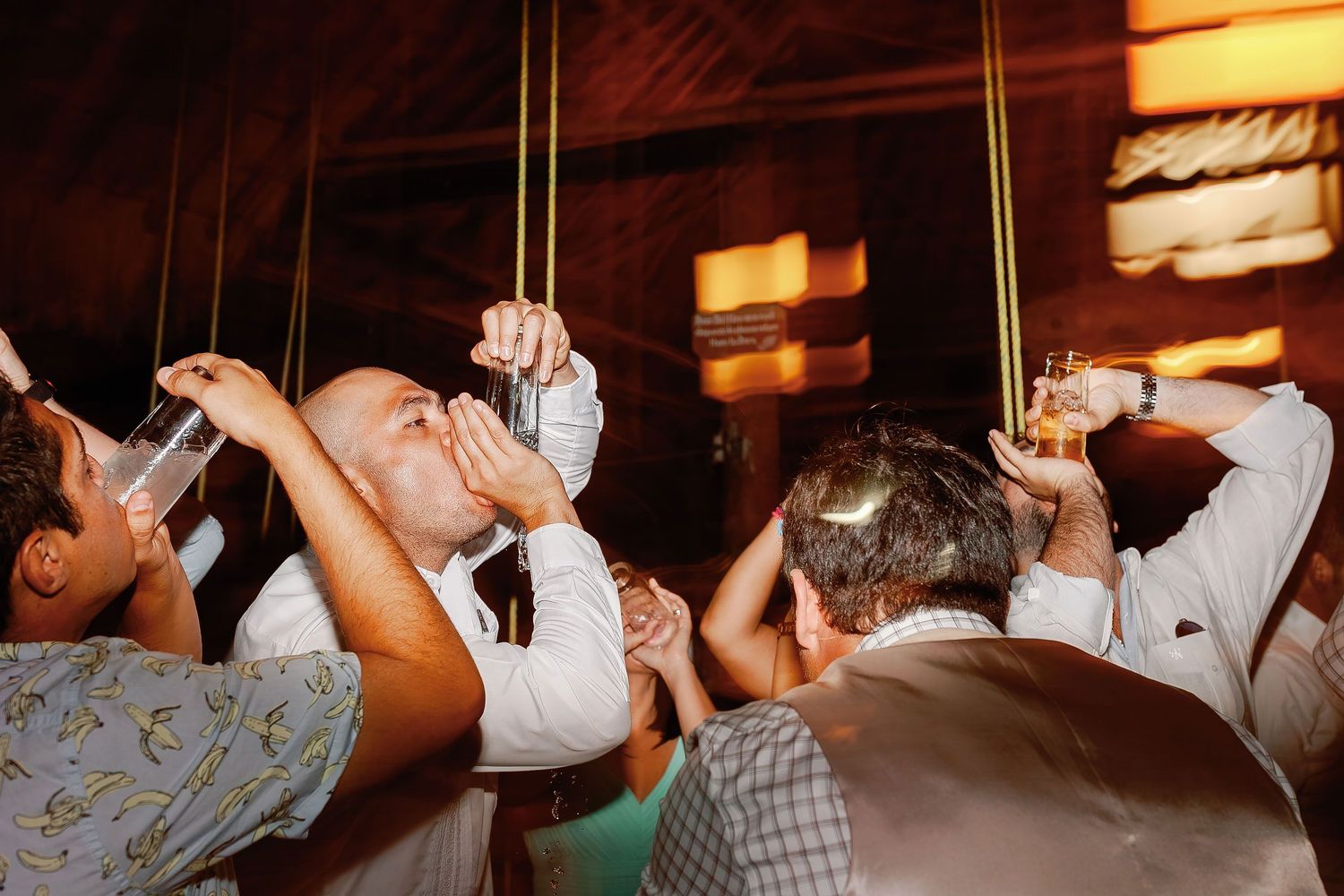 Wedding guests raise drinks during an energetic late-night celebration at the Playa Norte reception.