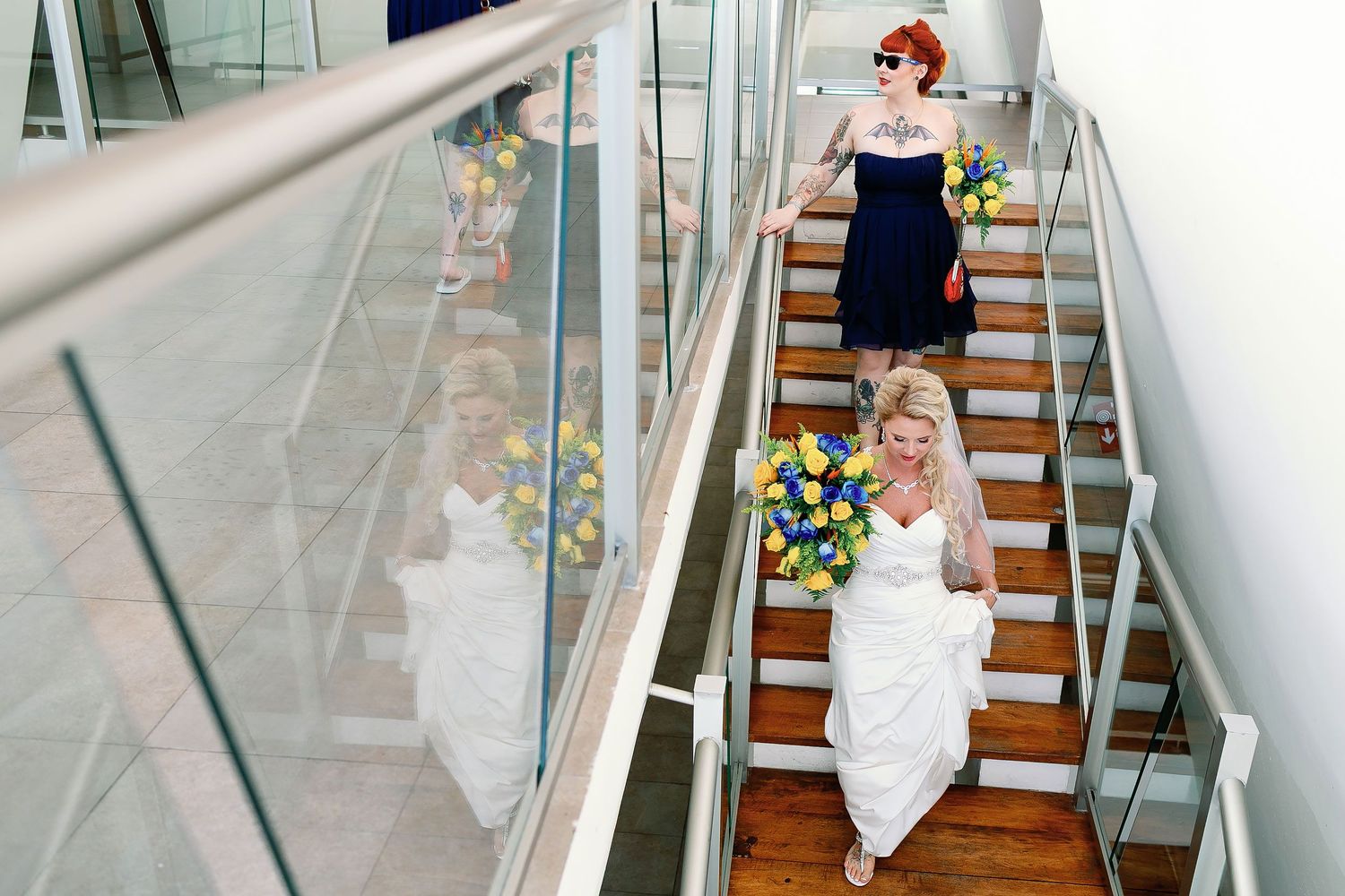 Carly carrying a colorful bouquet while walking downstairs with a bridesmaid