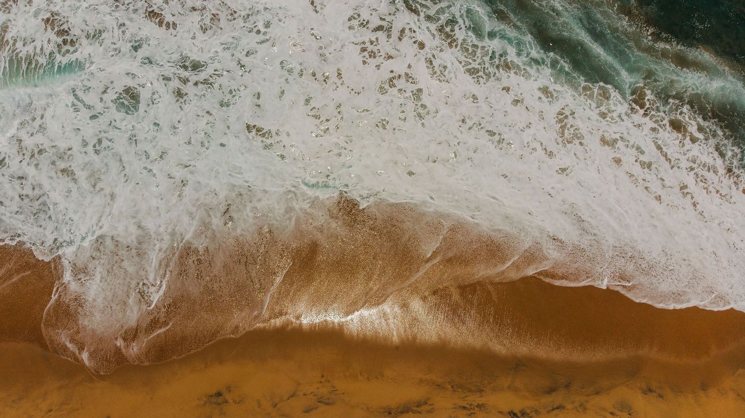 Aerial drone view of waves meeting the golden sand beaches of Puerto Vallarta along Mexico's stunning Pacific coastline.