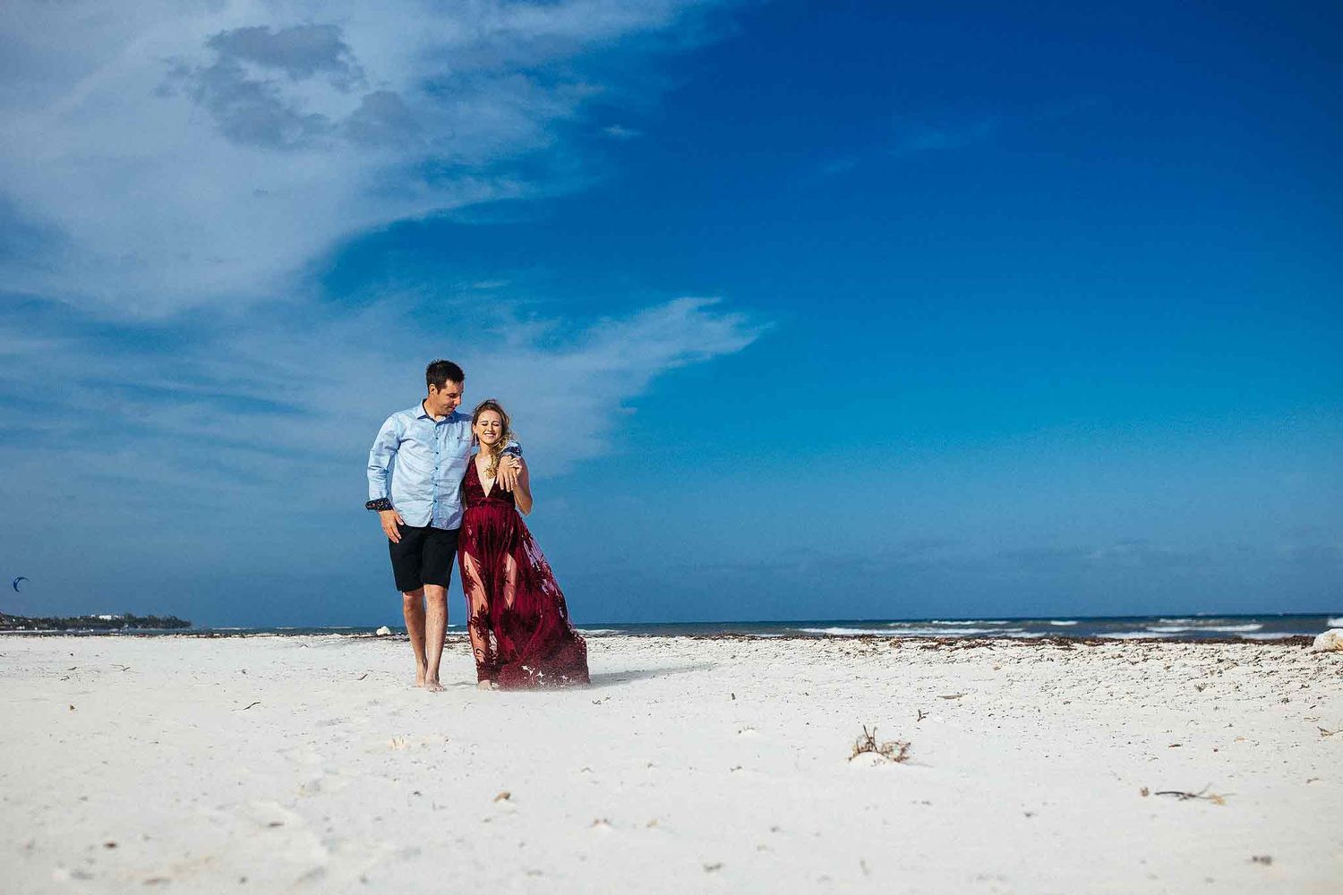 Engaged couple walking barefoot along the shoreline in Punta Esmeralda during a Playa del Carmen engagement shoot.