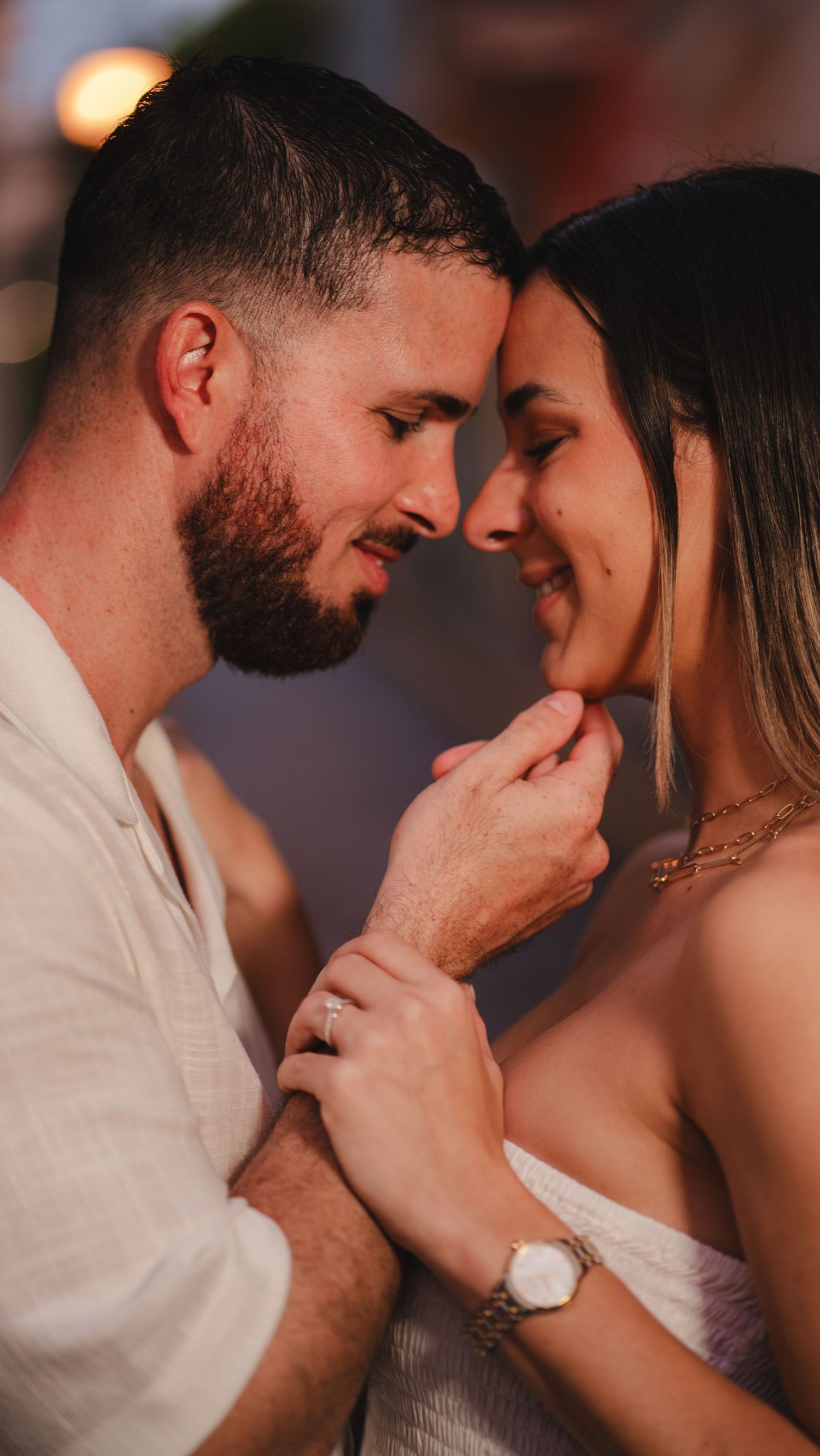 Close-up of an engaged couple nearly kissing, woman showing diamond ring.