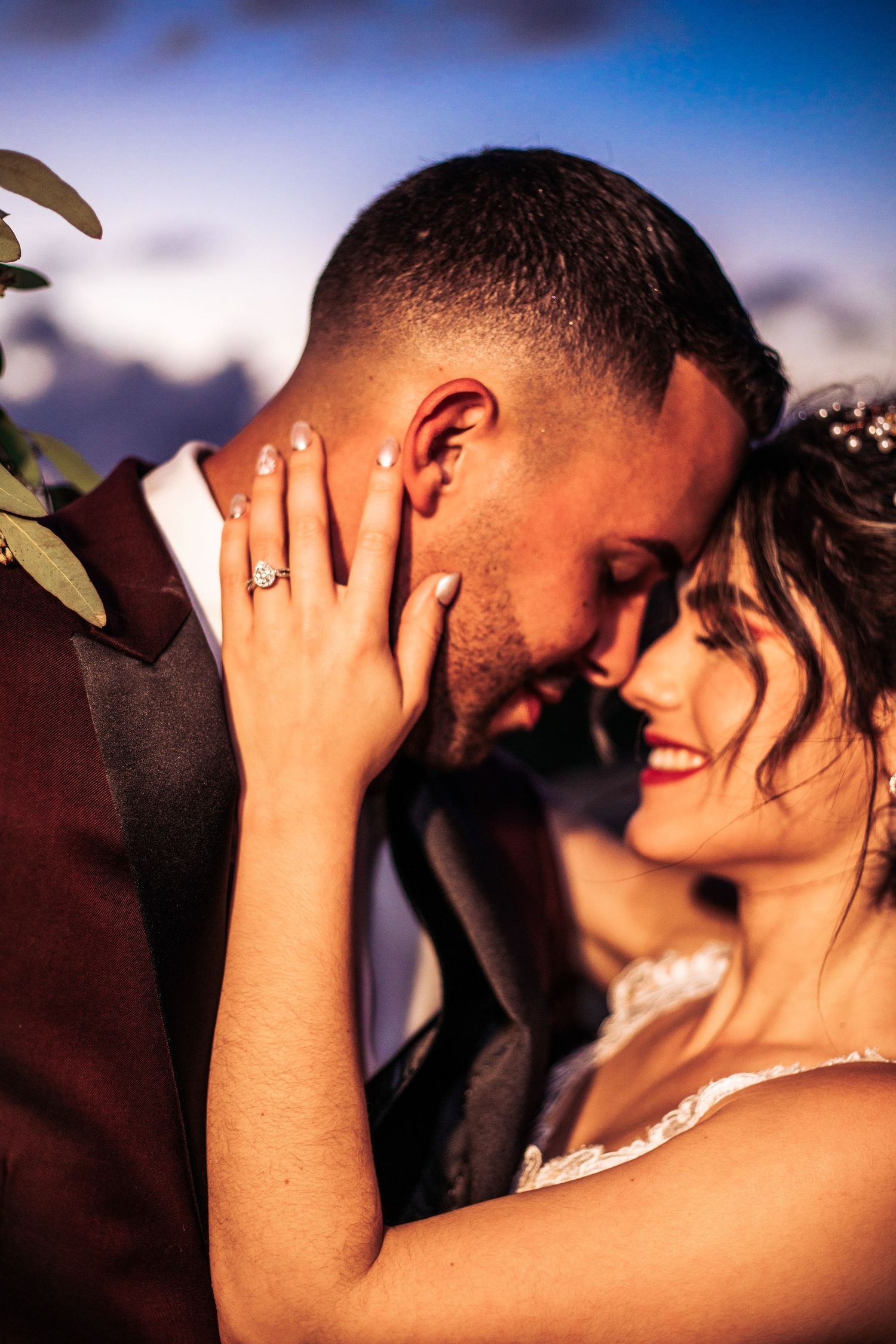Bride and groom sharing an intimate moment at sunset, bride showing ring.