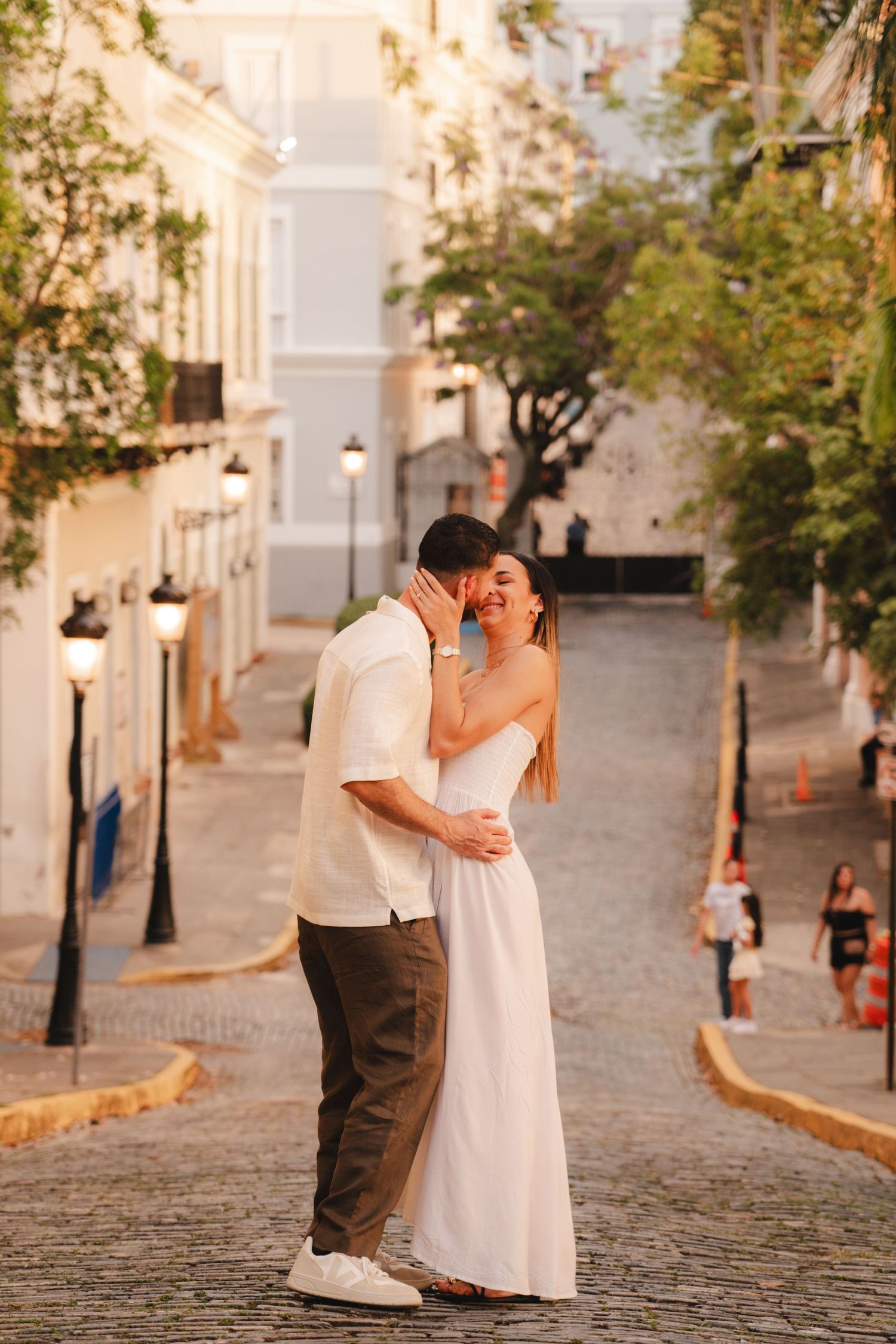 Romantic couple embracing on a cobblestone street in Old San Juan at golden hour.