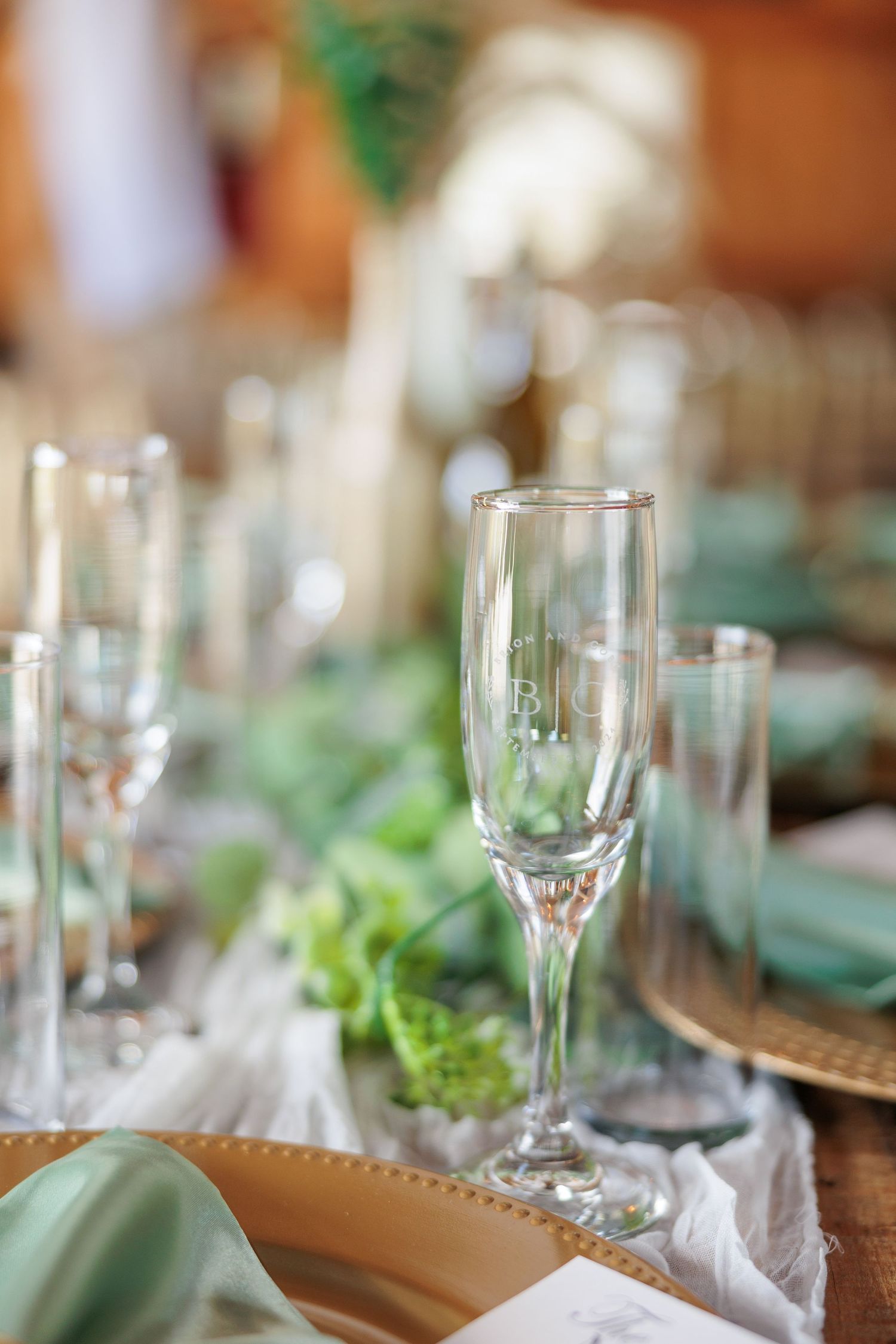 Elegant table settings with wine glasses and greenery decorations at a wedding reception.