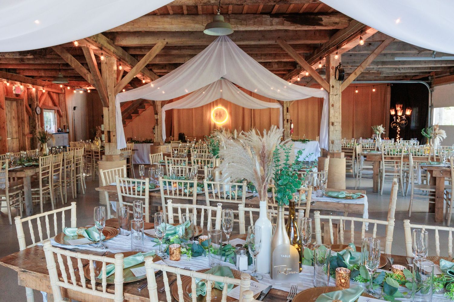 Elegant barn wedding reception setup with white chairs and teal accents.