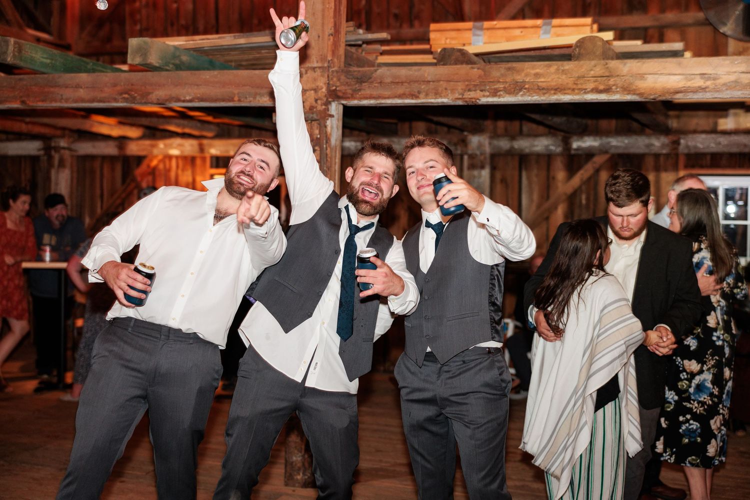Wedding party having fun and making silly faces in rustic barn venue.