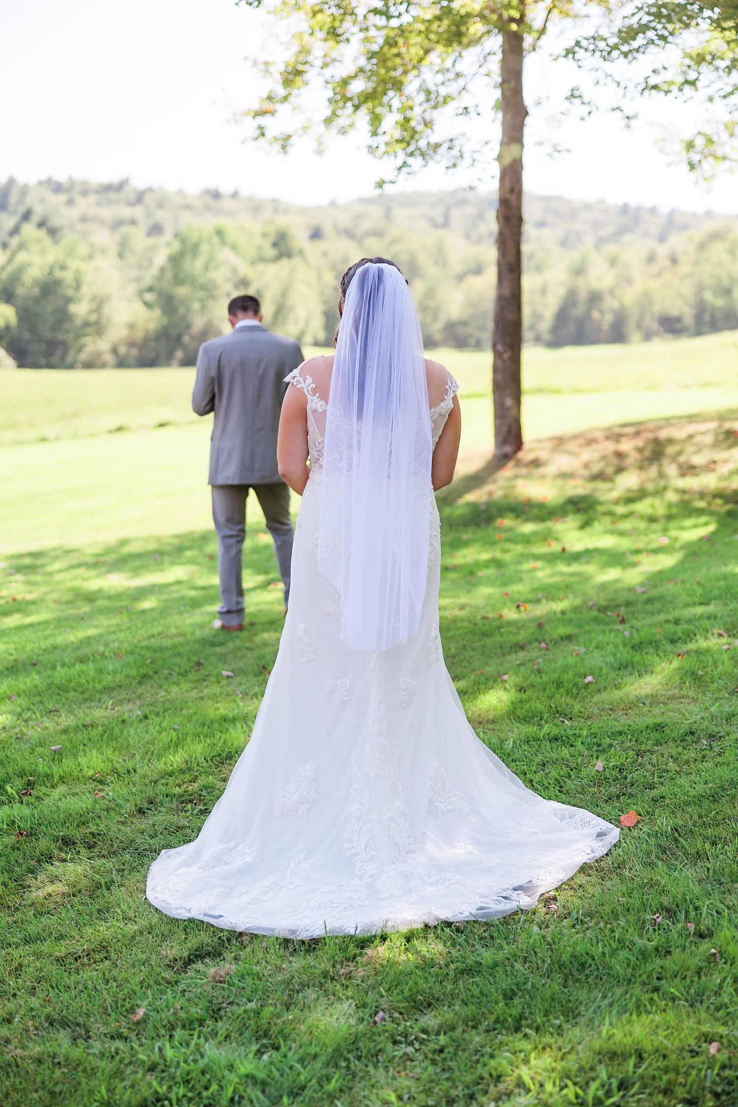 Bride and groom walk away together across green lawn before first look.