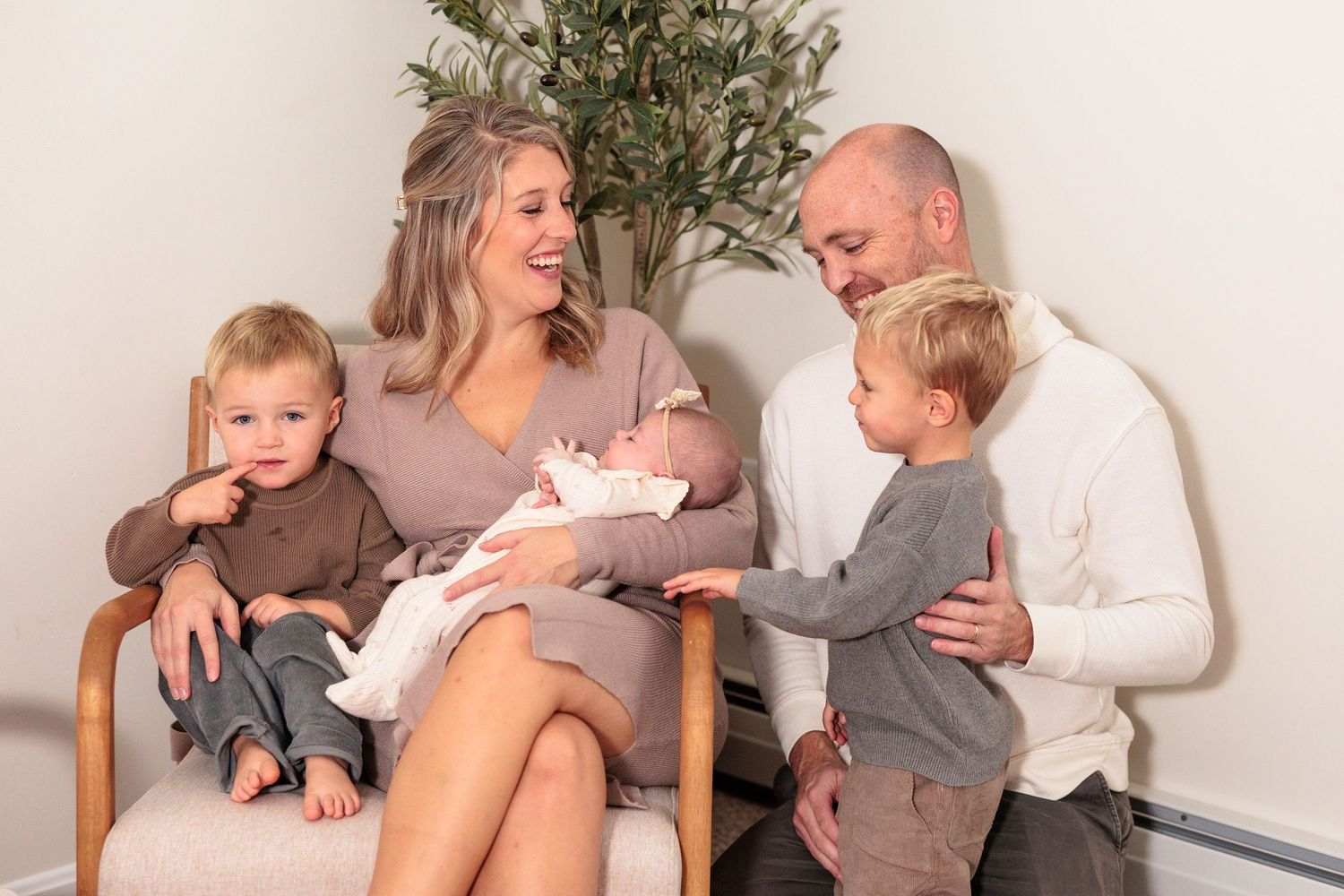 Family sitting together on floor with indoor plant in background.