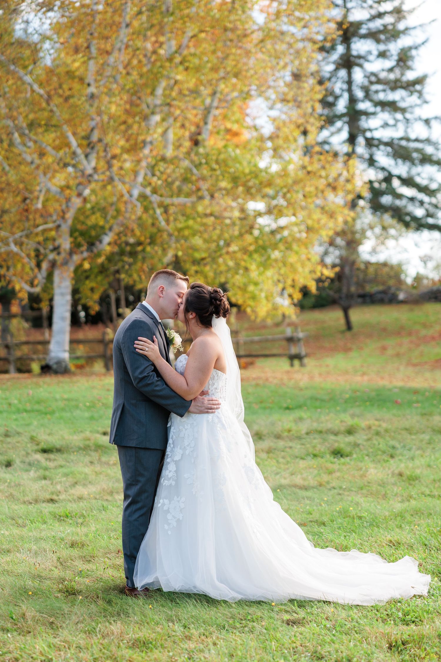 A couple shares intimate moments in a fall outdoor setting with golden leaves in the background.