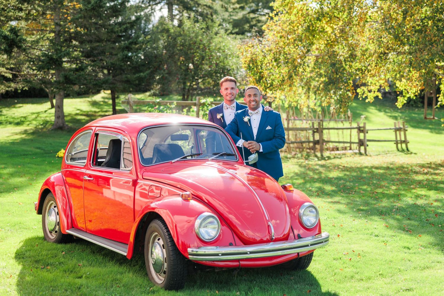 Classic red Volkswagen Beetle featured in wedding photography on green lawn.