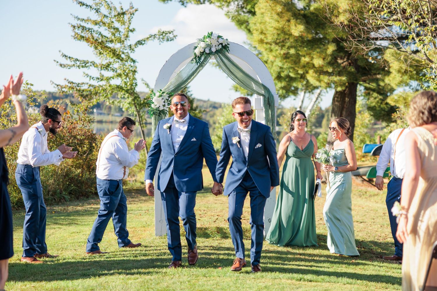 Outdoor wedding ceremony setup with white chairs and floral arch against a natural landscape.
