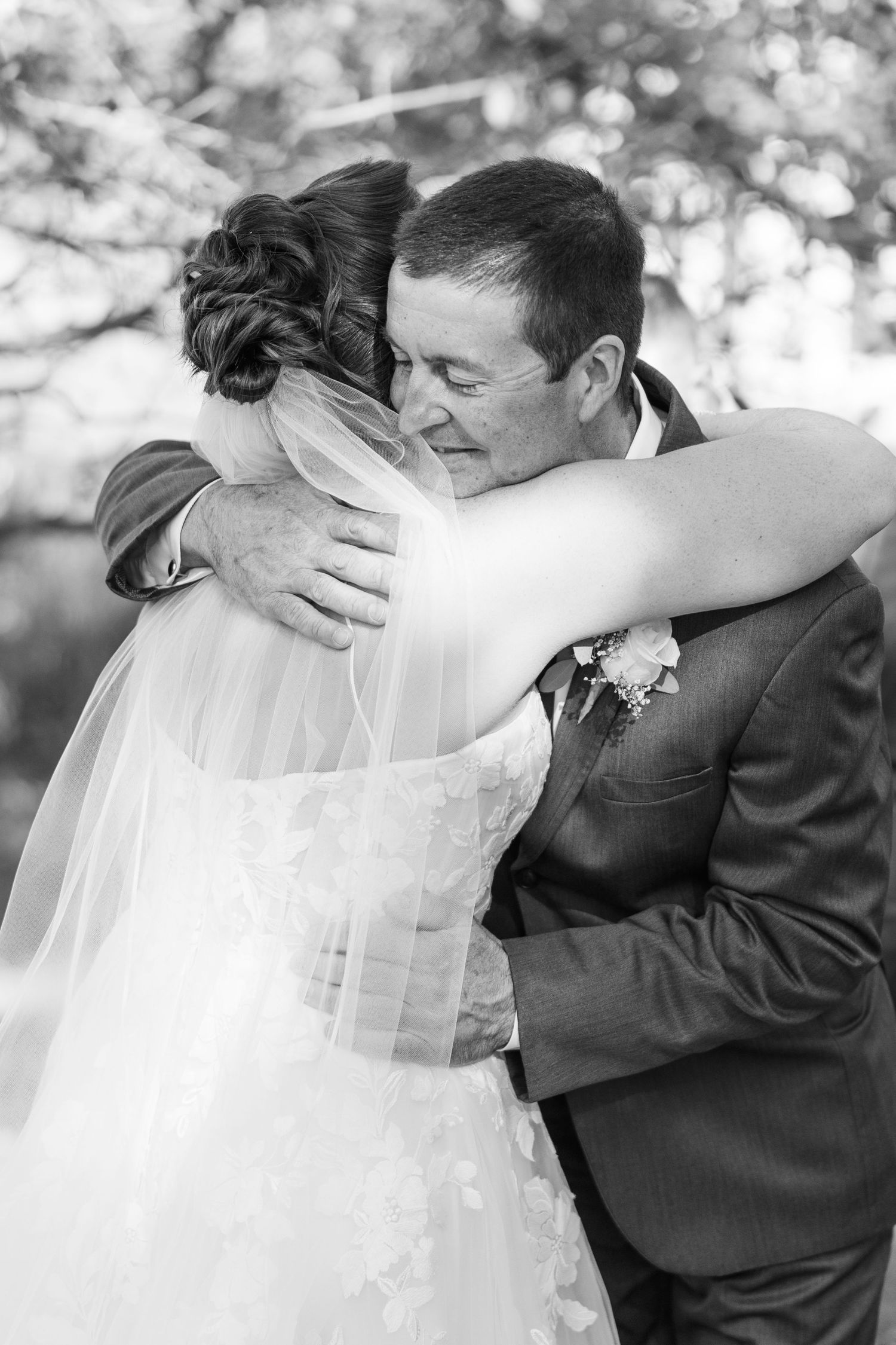 Emotional black and white photo of bride and father sharing a hug before wedding ceremony.