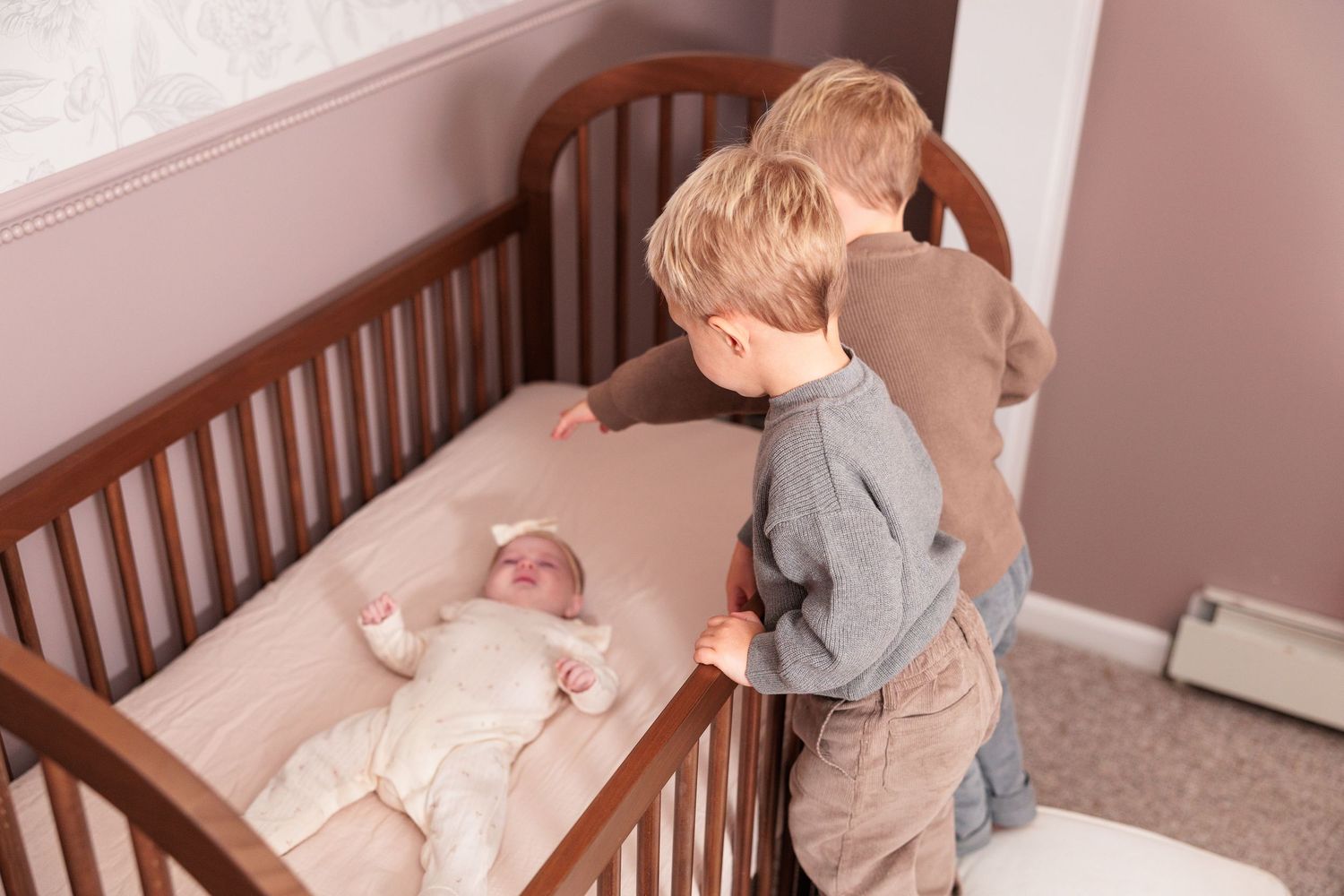 Collection of photos capturing tender moments between family members near a wooden crib.