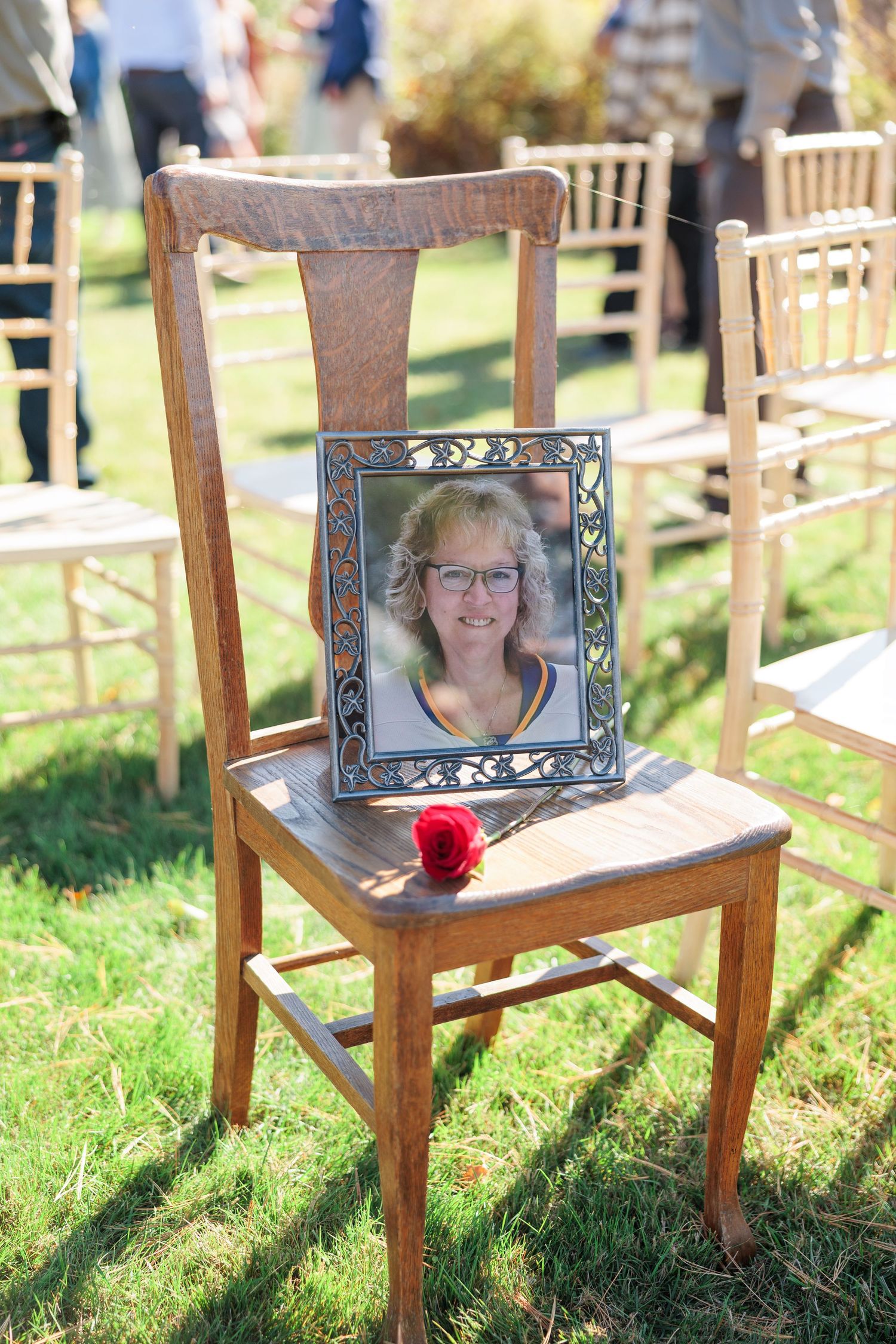 Empty wooden chairs with picture frames displayed at an outdoor wedding ceremony in autumn.