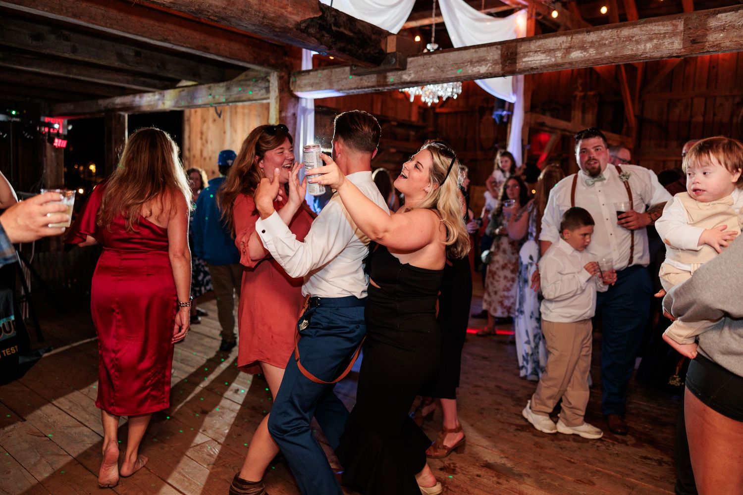 Guests enjoying a festive dance party under warm lighting at a rustic indoor venue.