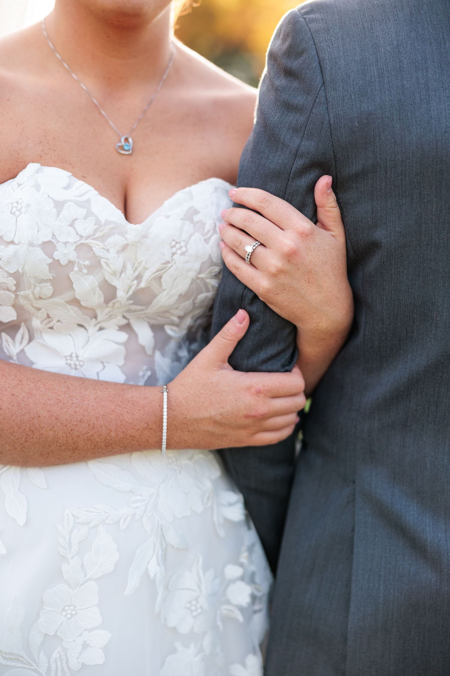 Close-up detail of a couple in wedding attire showing white bridal gown and dark gray suit.
