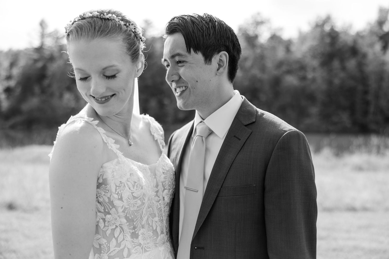 Black and white portrait of smiling bride and groom sharing a joyful moment outdoors on their wedding day.