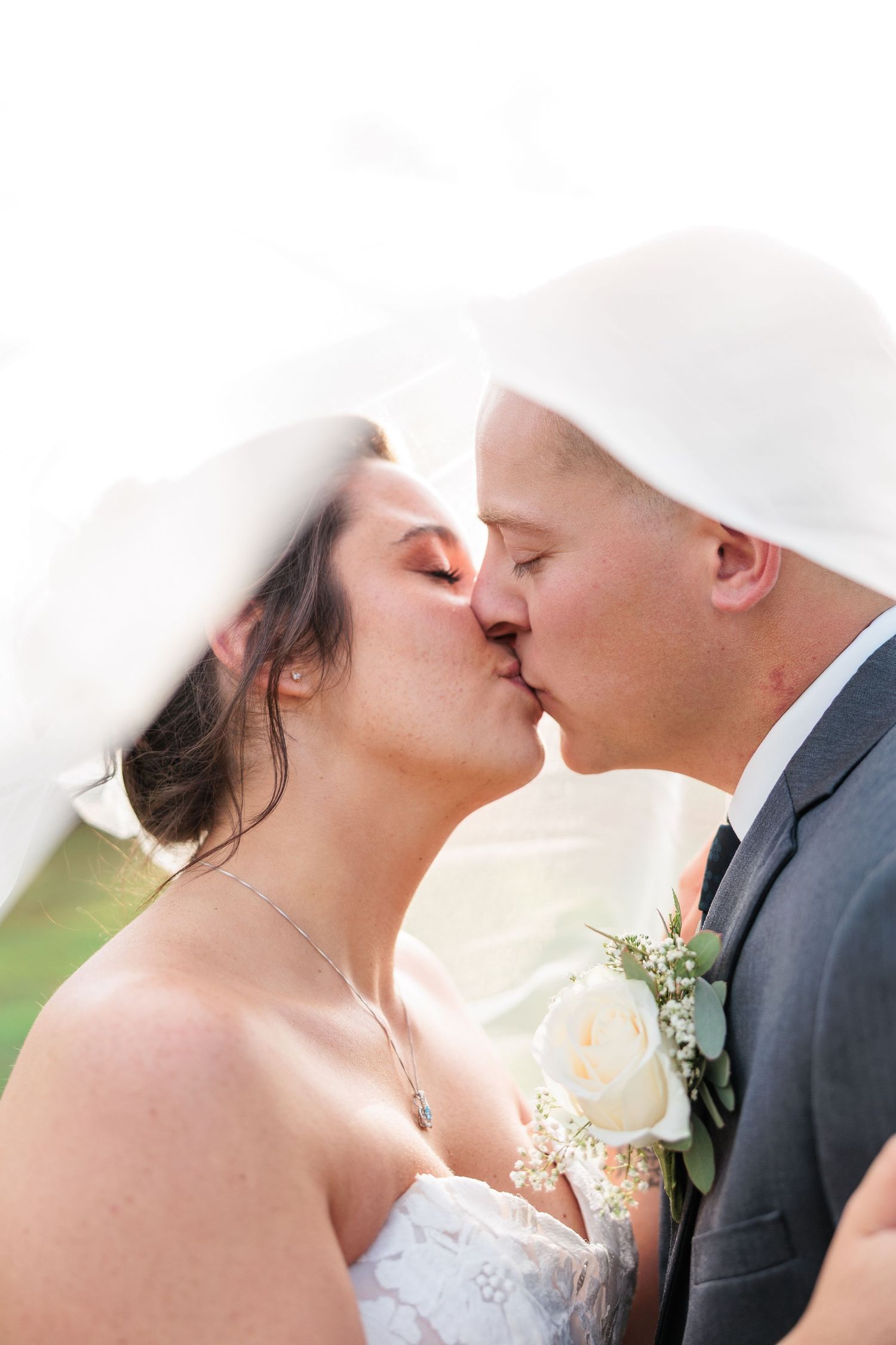 A romantic wedding kiss captured under a flowing white veil.