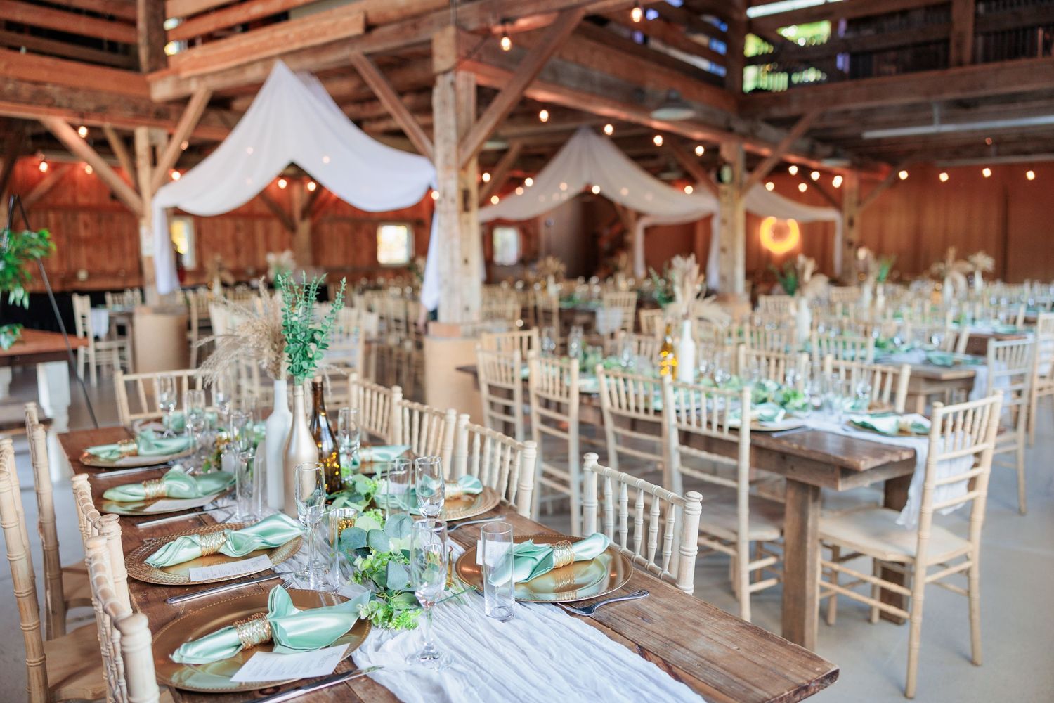Rustic barn wedding reception venue with white chairs and elegant table settings.