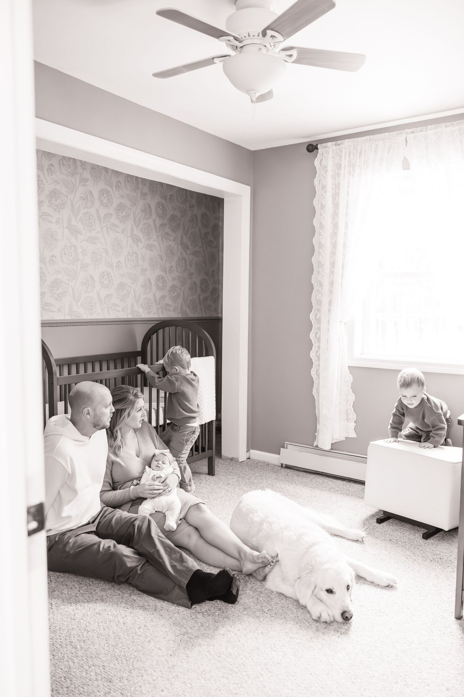 Panoramic view of a modern bedroom with ceiling fan and family relaxing on floor.