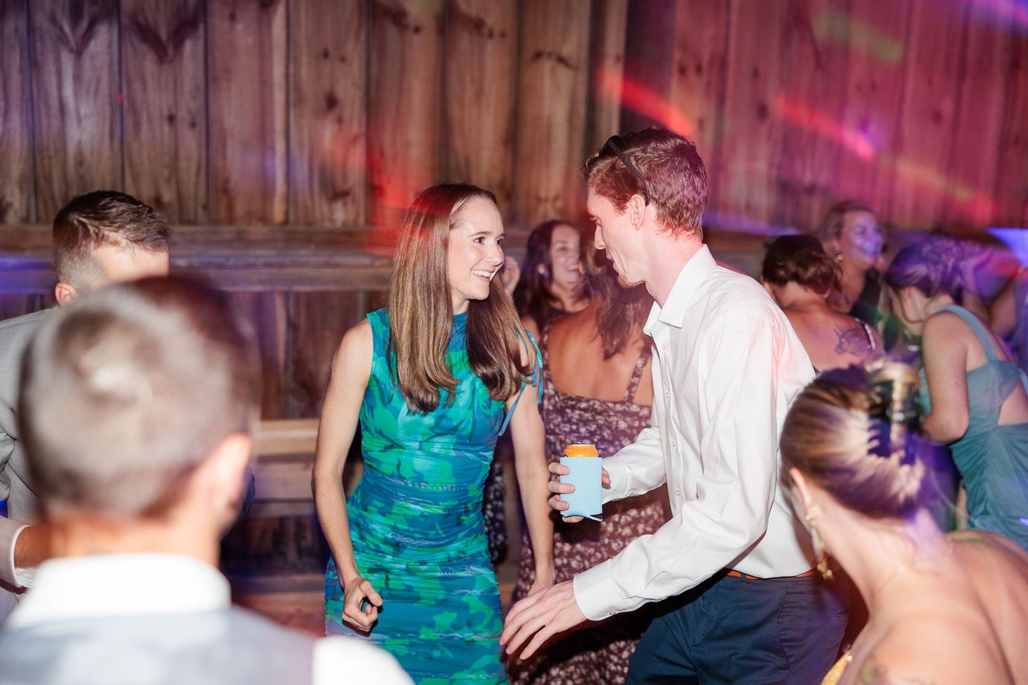 Couple shares a joyful moment dancing together at colorful wedding reception in rustic barn venue.