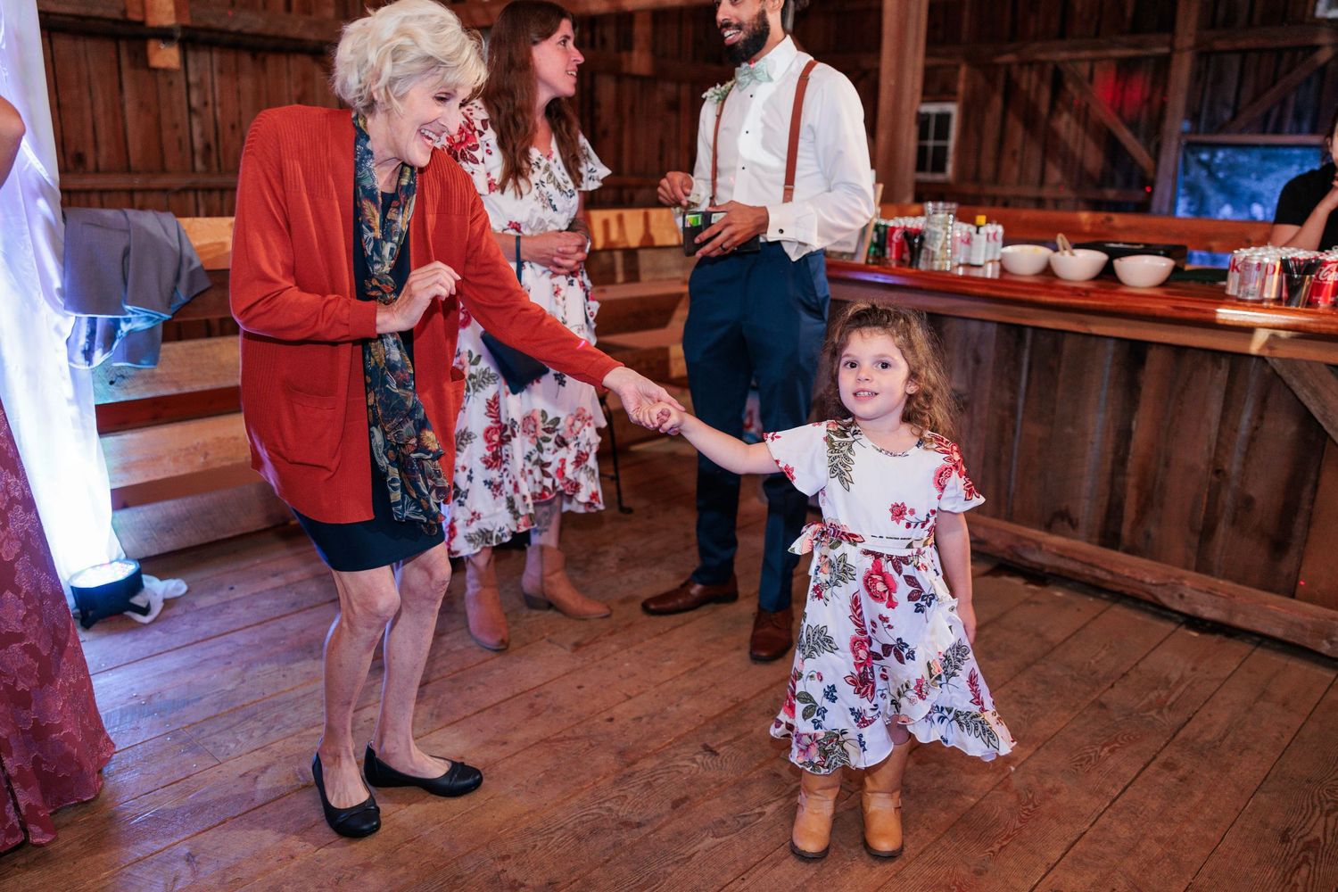 People dancing and mingling at a rustic barn wedding reception.