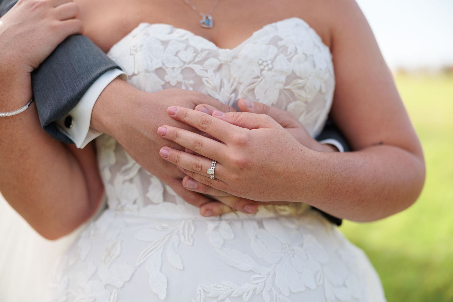 Close-up detail of bride's lace dress and jewelry accessories.