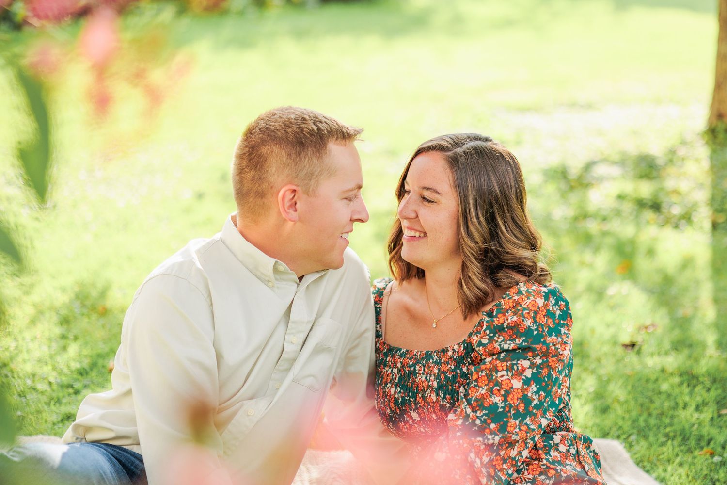 Laughing couple sharing a joyful moment together during sunny outdoor engagement photography session.