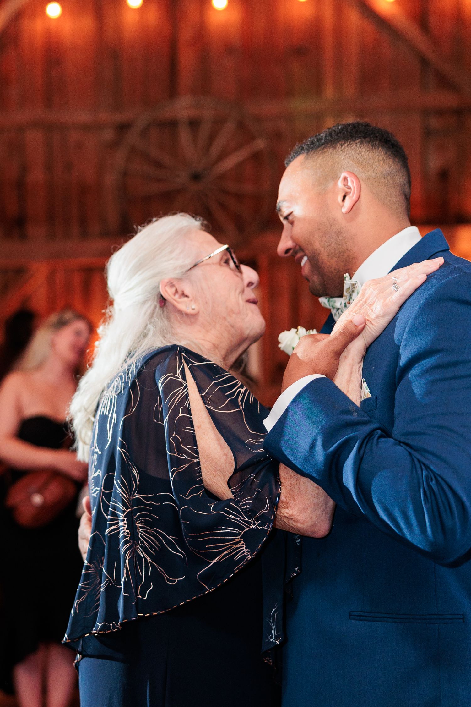 Dance partners performing a dip move during a celebration in a warmly lit barn setting.