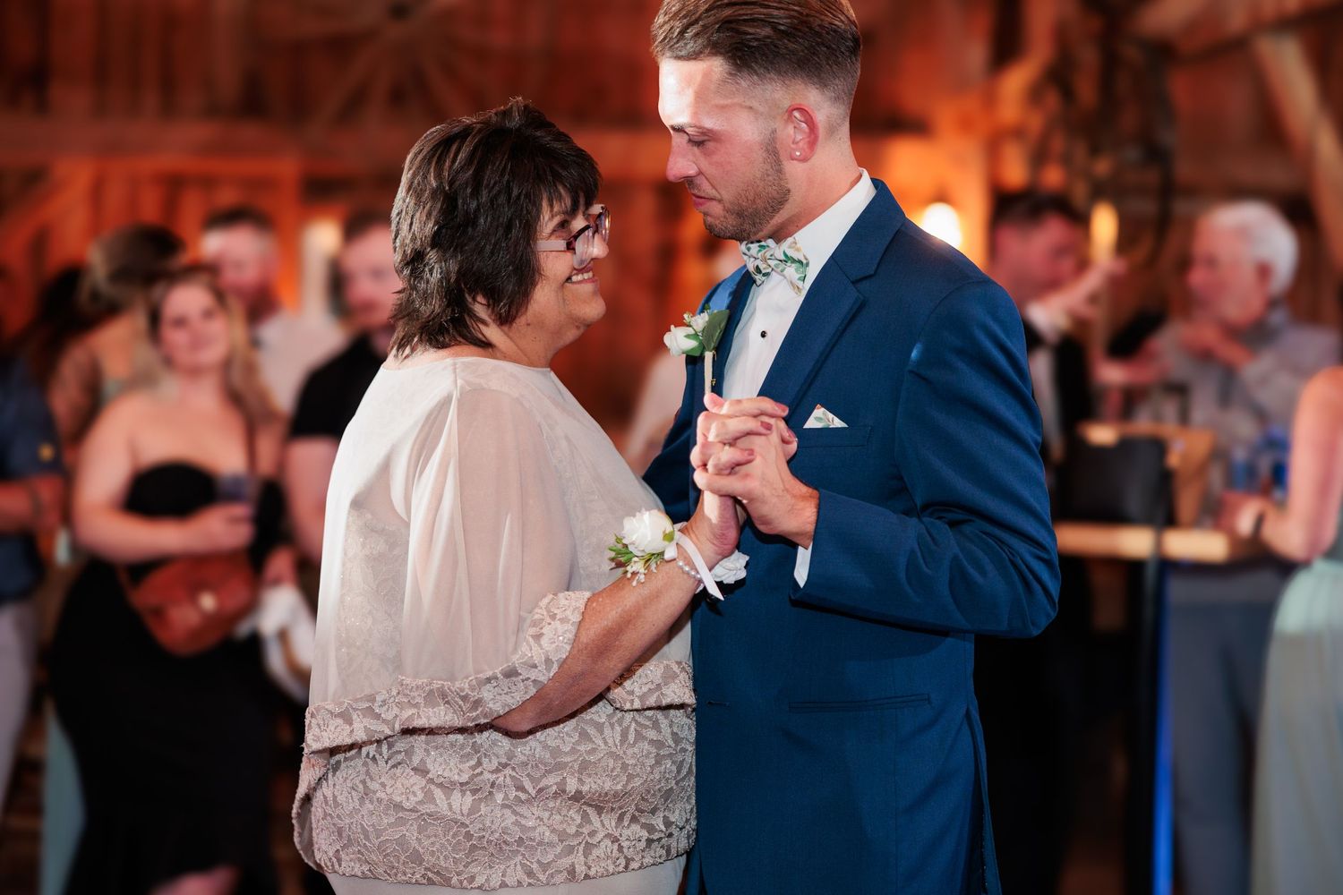 Couples dance together during a wedding reception in a rustic barn setting.