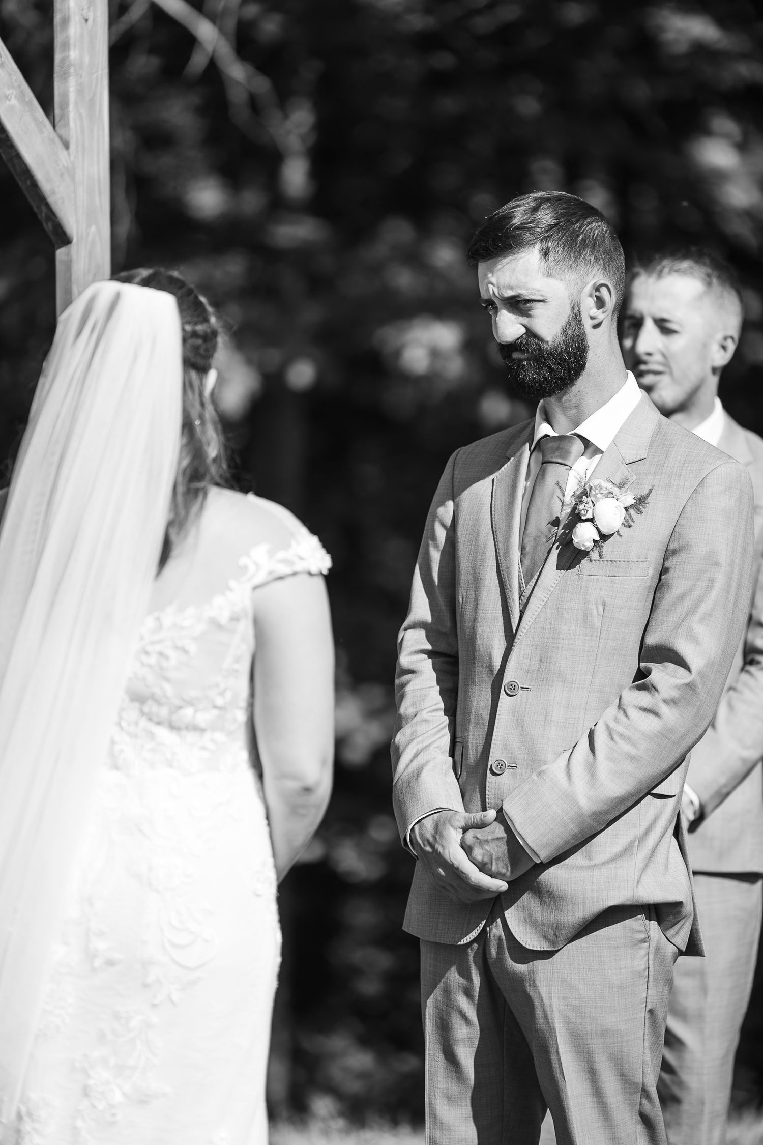 Bearded groom gazes lovingly at bride during intimate outdoor wedding ceremony in classic black and white.