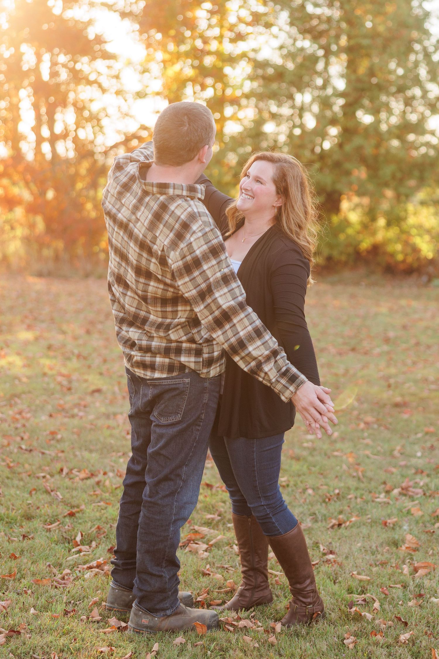 Couple dancing outdoors in autumn park with golden sunset light filtering through colorful fall foliage.
