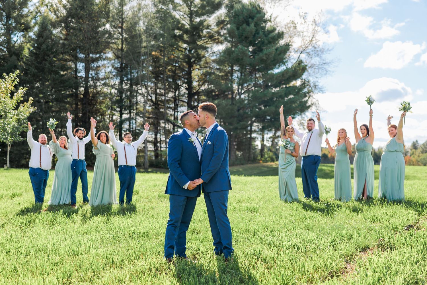 Wedding party spreads out on grass with coordinated mint and navy outfits for creative photo composition.