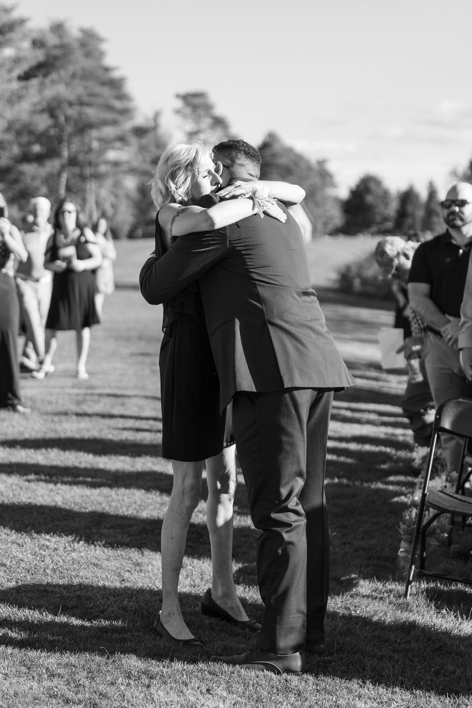 Wedding guests mingling on a grassy lawn during an outdoor reception.