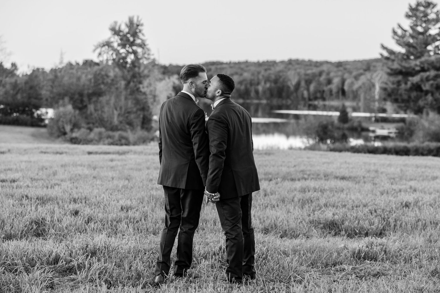 Black and white photo of a couple standing together in a field during their wedding ceremony.