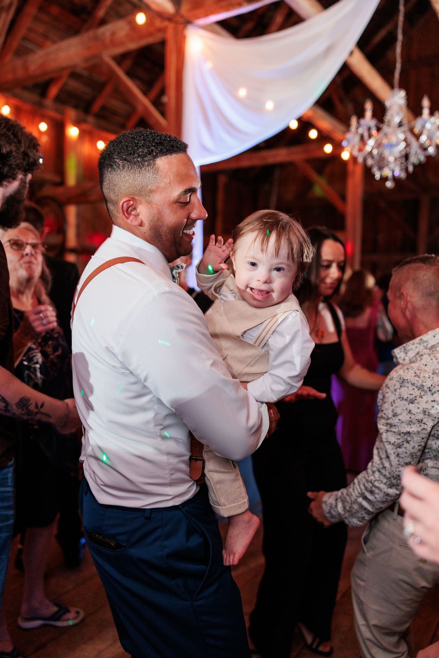 Lively dancing and celebration inside a barn venue decorated with string lights.
