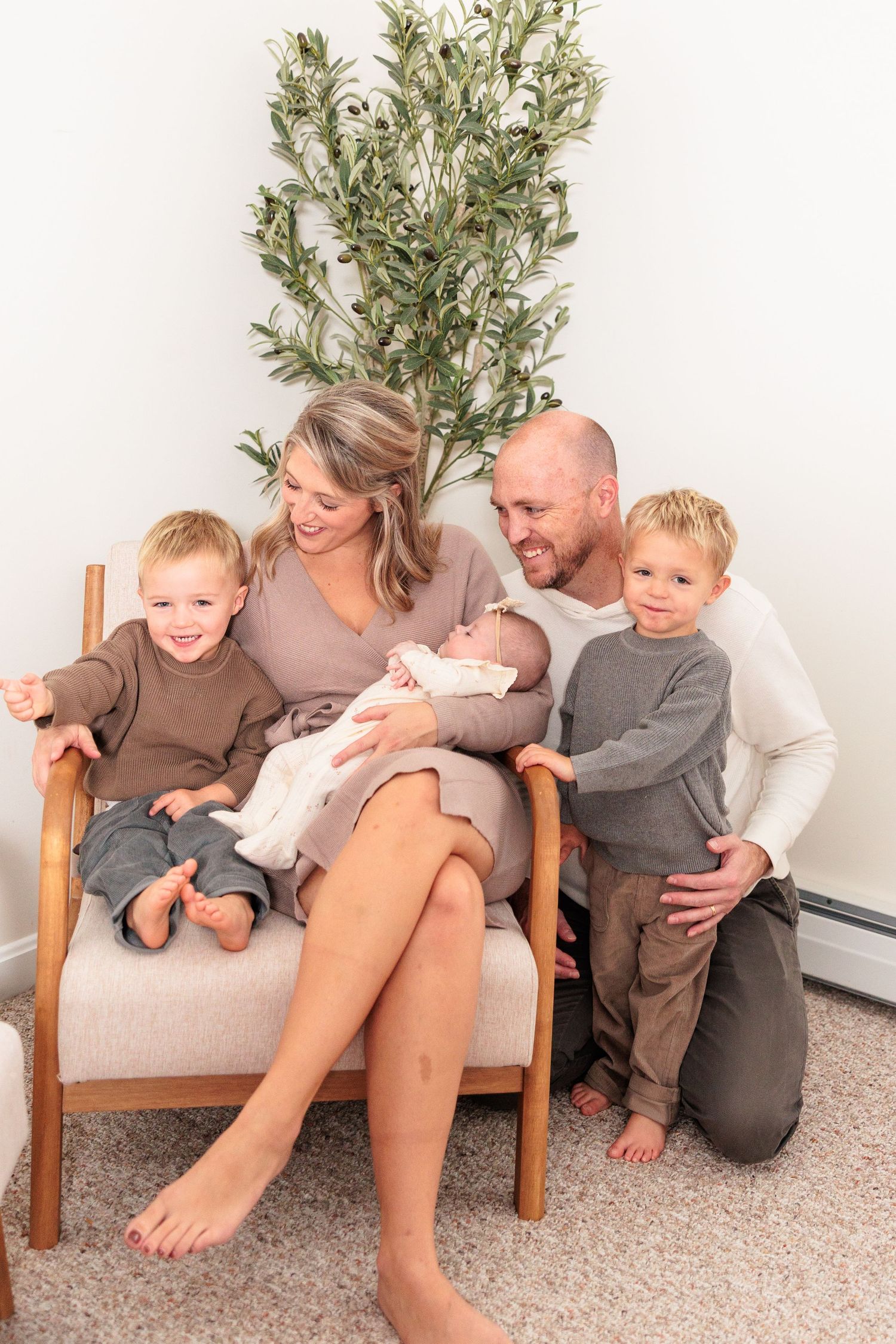 A loving family shares tender moments together on a carpeted floor with a decorative plant in the background.