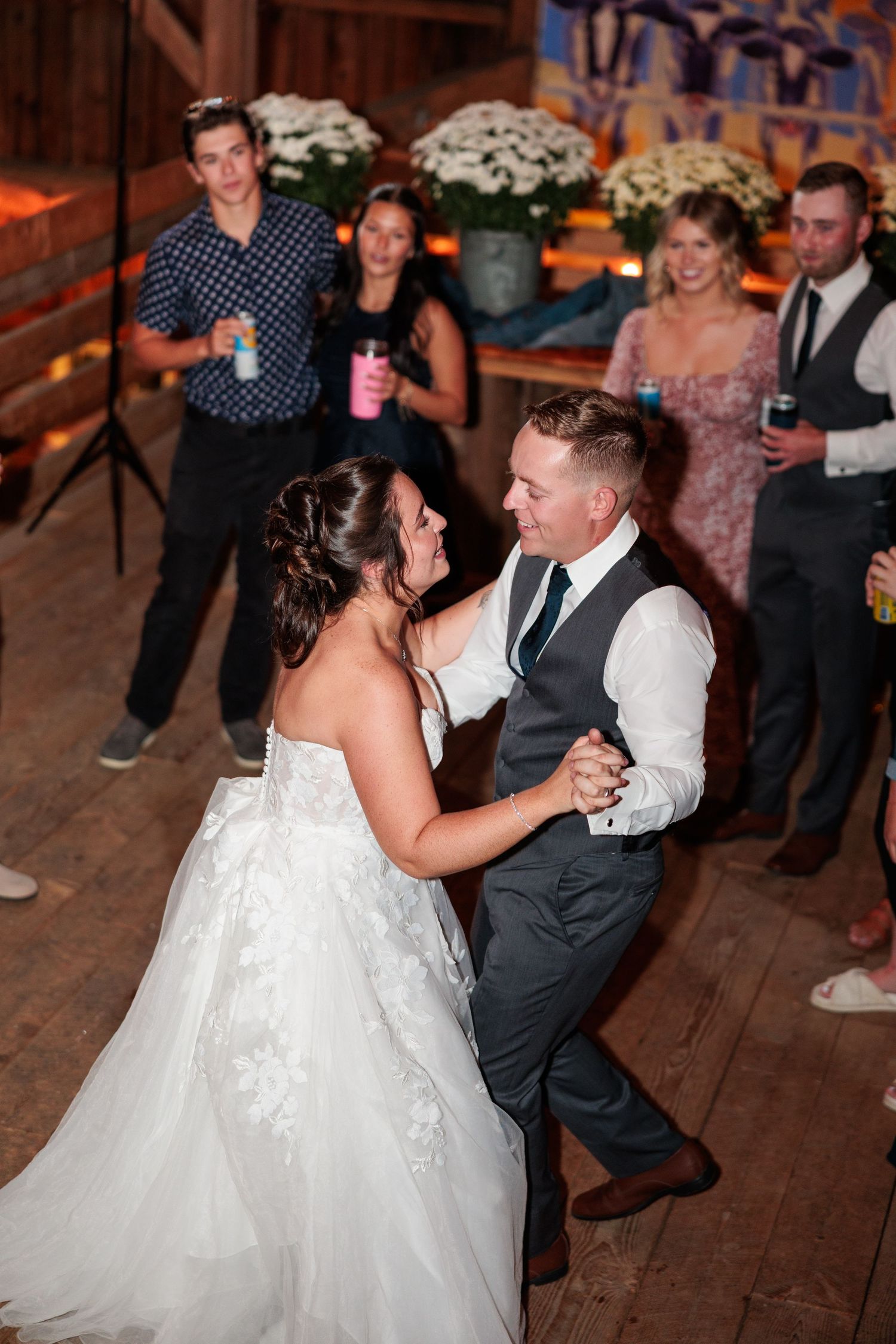 Wedding reception dance features couple twirling on a rustic wooden dance floor under chandelier lighting.