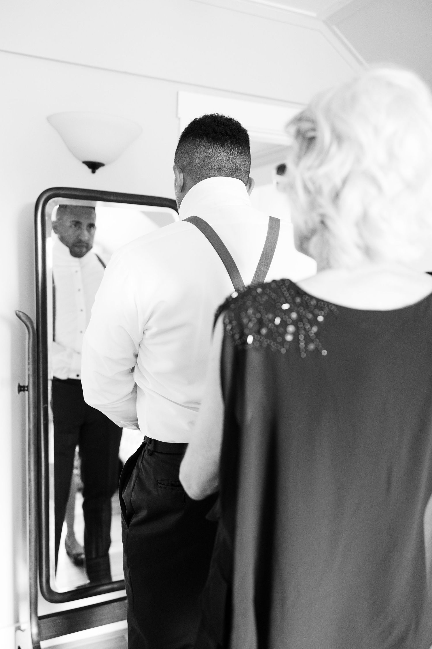Wedding party members in formal attire gathered near a mirror.