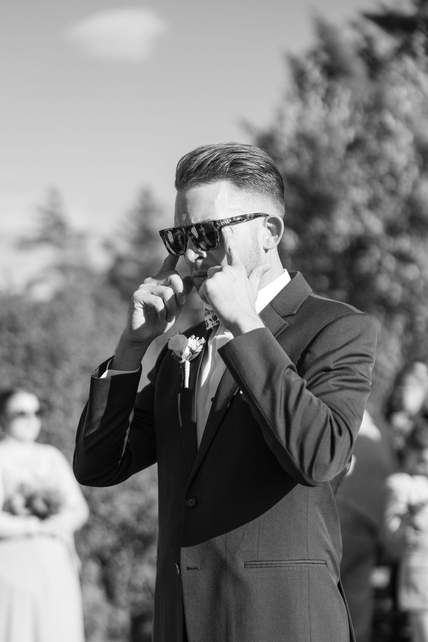 Black and white photo showing emotional reactions through binoculars at an outdoor event.