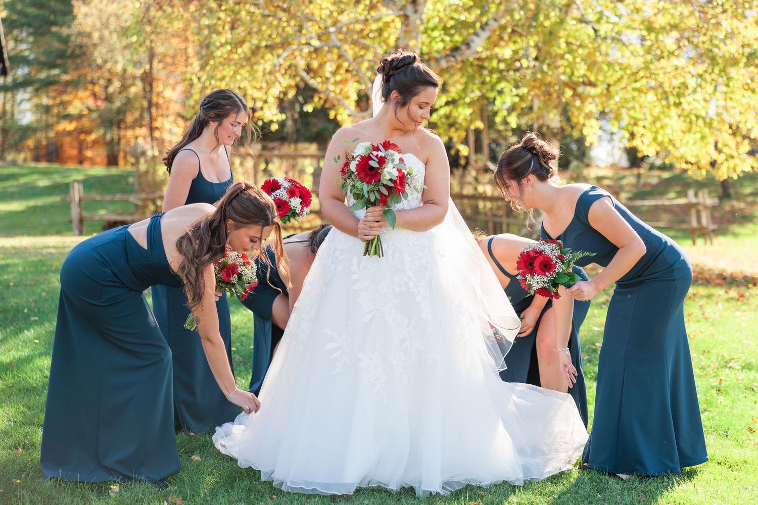 Bridal party in navy blue dresses and white wedding gown pose together outdoors during fall season.
