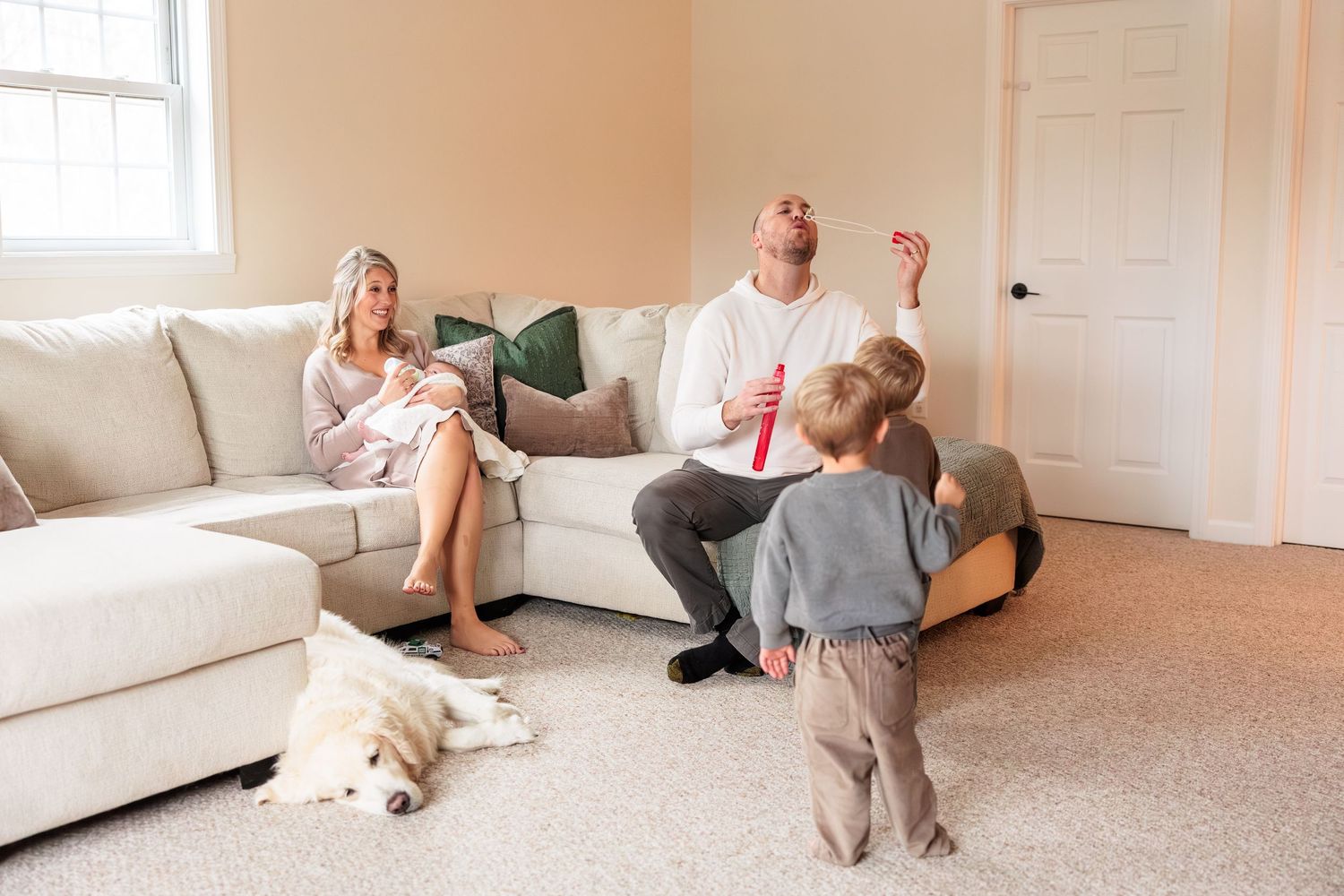 Family relaxing together on white furniture in a bright, airy living room.