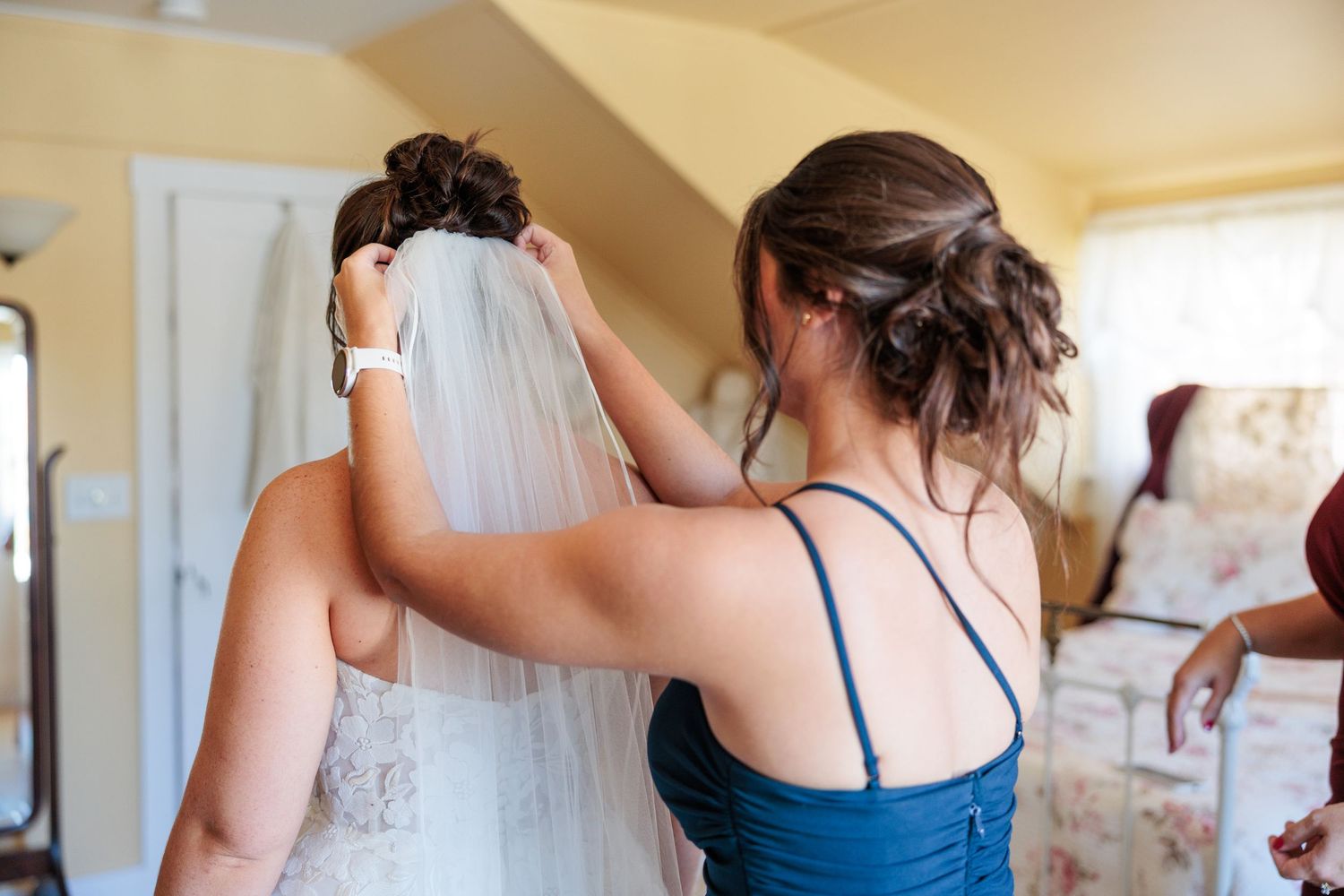 Bridesmaids in navy blue dresses help with wedding preparations.